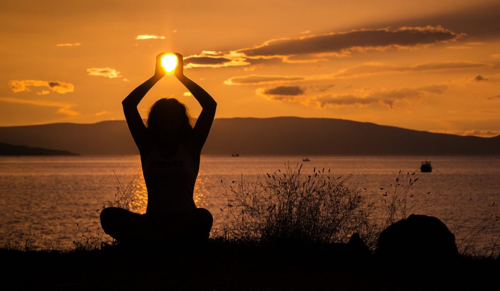 persona in posizione di yoga al tramonto